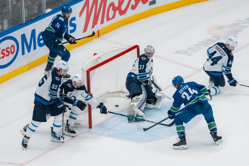 Mar 18, 2025; Vancouver, British Columbia, CAN; Winnipeg Jets forward Mark Scheifele (55) and defenseman Dylan DeMelo (2) and defenseman Josh Morrissey (44) and Vancouver Canucks forward Jake DeBrusk (74) watch as  forward Pius Suter (24) scores on goalie Connor Hellebuyck (37) in the second period at Rogers Arena. Mandatory Credit: Bob Frid-Imagn Images