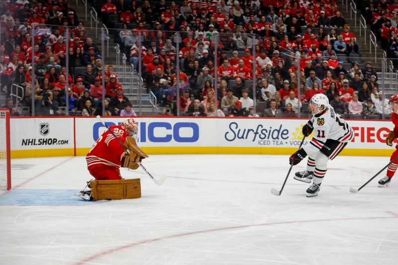 Nov 9, 2025; Detroit, Michigan, USA; Chicago Blackhawks center Oliver Moore (11) takes a shot on Detroit Red Wings goaltender John Gibson (36) during the first period at Little Caesars Arena. Mandatory Credit: Brian Bradshaw Sevald-Imagn Images