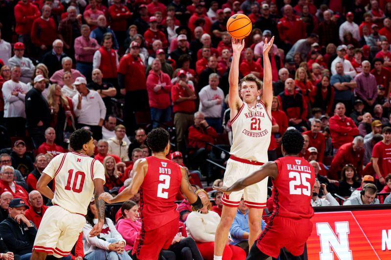 Dec 10, 2025; Lincoln, Nebraska, USA; Nebraska Cornhuskers forward Pryce Sandfort (21) shoots a three point basket against Wisconsin Badgers guard Nick Boyd (2) and guard John Blackwell (25) during the first half at Pinnacle Bank Arena. Mandatory Credit: Dylan Widger-Imagn Images