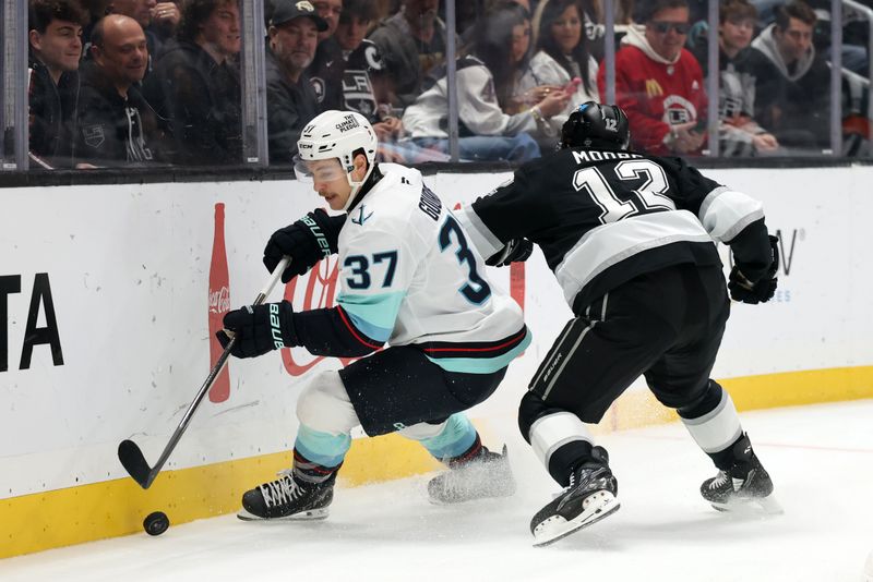 Nov 23, 2024; Los Angeles, California, USA;  Seattle Kraken center Yanni Gourde (37) controls the puck against Los Angeles Kings left wing Trevor Moore (12) during the first period at Crypto.com Arena. Mandatory Credit: Kiyoshi Mio-Imagn Images