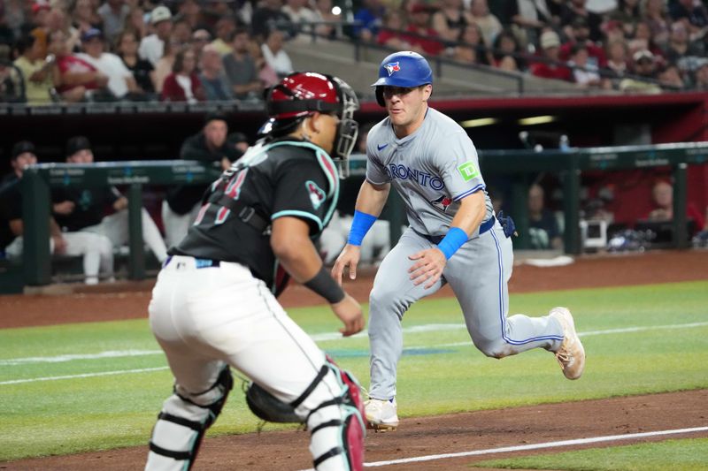 Jul 12, 2024; Phoenix, Arizona, USA; Toronto Blue Jays outfielder Daulton Varsho (25) beats a throw to Arizona Diamondbacks catcher Gabriel Moreno (14) to score a run during the seventh inning at Chase Field. Mandatory Credit: Joe Camporeale-USA TODAY Sports