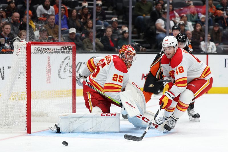 Dec 21, 2023; Anaheim, California, USA;  Calgary Flames defenseman Dennis Gilbert (48) chases the puck as goaltender Jacob Markstrom (25) defends the goal during the second period against the Anaheim Ducks at Honda Center. Mandatory Credit: Kiyoshi Mio-USA TODAY Sports