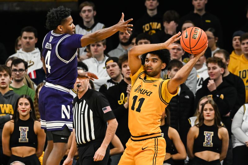 Feb 8, 2026; Iowa City, Iowa, USA; Northwestern Wildcats guard Jayden Reid (4) defends Iowa Hawkeyes guard Kael Combs (11) during the first half at Carver-Hawkeye Arena. Mandatory Credit: Jeffrey Becker-Imagn Images