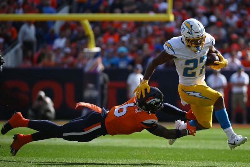 Los Angeles Chargers running back J.K. Dobbins (27) runs with the football as Denver Broncos safety P.J. Locke (6) tries to tackle during the first half of an NFL football game, Sunday, Oct. 13, 2024, in Denver. (AP Photo/Geneva Heffernan)