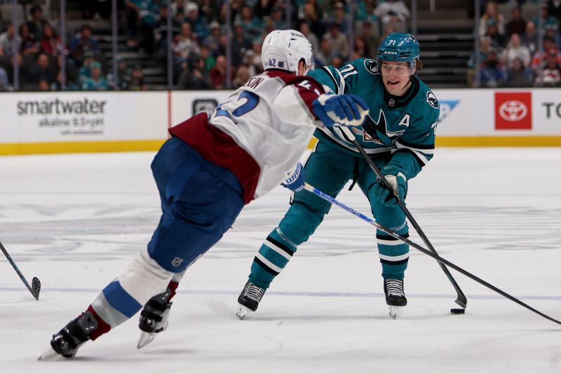 Nov 1, 2025; San Jose, California, USA; San Jose Sharks center Macklin Celebrini (71) plays the puck against Colorado Avalanche center Josh Manson (42) during the first period at SAP Center at San Jose. Mandatory Credit: Dennis Lee-Imagn Images