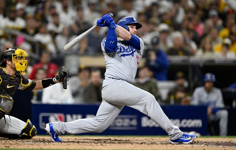 Oct 9, 2024; San Diego, California, USA; Los Angeles Dodgers third baseman Max Muncy (13) hits a double in the third inning against the San Diego Padres during game four of the NLDS for the 2024 MLB Playoffs at Petco Park.  Mandatory Credit: Denis Poroy-Imagn Images