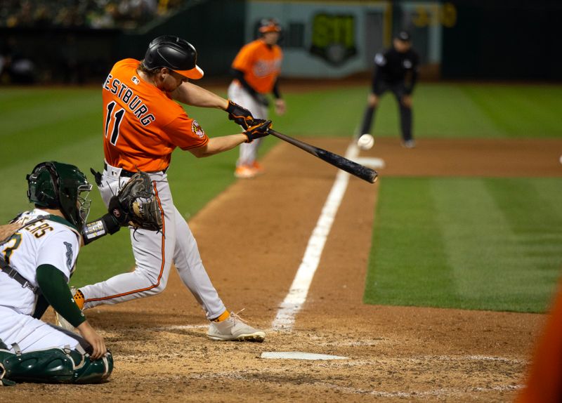 Aug 19, 2023; Oakland, California, USA; Baltimore Orioles second baseman Jordan Westburg (11) hits a sacrifice fly against the Oakland Athletics during the 10th inning at Oakland-Alameda County Coliseum. Mandatory Credit: D. Ross Cameron-USA TODAY Sports