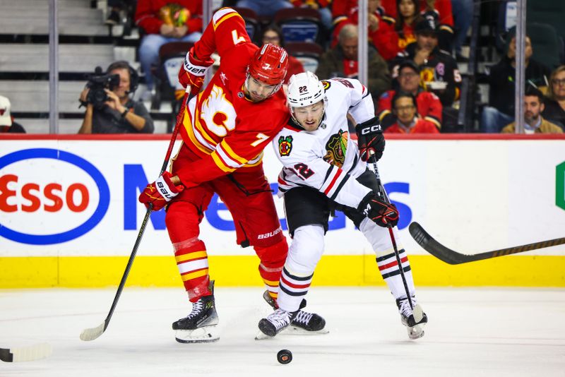 Oct 15, 2024; Calgary, Alberta, CAN; Calgary Flames defenseman Kevin Bahl (7) and Chicago Blackhawks right wing Joey Anderson (22) battles for the puck during the first period at Scotiabank Saddledome. Mandatory Credit: Sergei Belski-Imagn Images