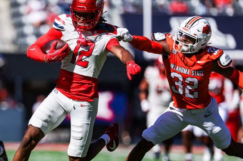 Oct 4, 2025; Tucson, Arizona, USA; Oklahoma State Cowboys safety Mordecai McDaniel (32) grabs Arizona Wildcats wide receiver Tre Spivey (12) during the third quarter of the game at Arizona Stadium. Mandatory Credit: Aryanna Frank-Imagn Images