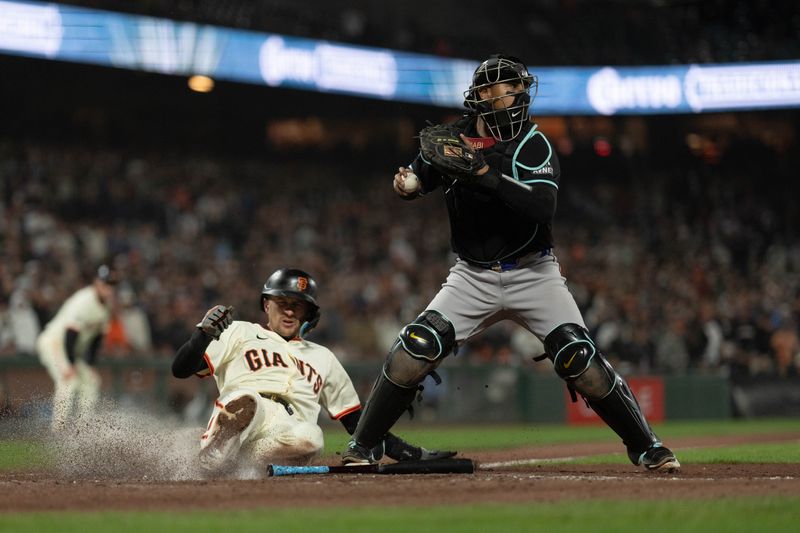 Apr 18, 2024; San Francisco, California, USA;  San Francisco Giants shortstop Nick Ahmed (16) slides at home on a force tag by Arizona Diamondbacks catcher Gabriel Moreno (14) during the eighth inning at Oracle Park. Mandatory Credit: Stan Szeto-USA TODAY Sports