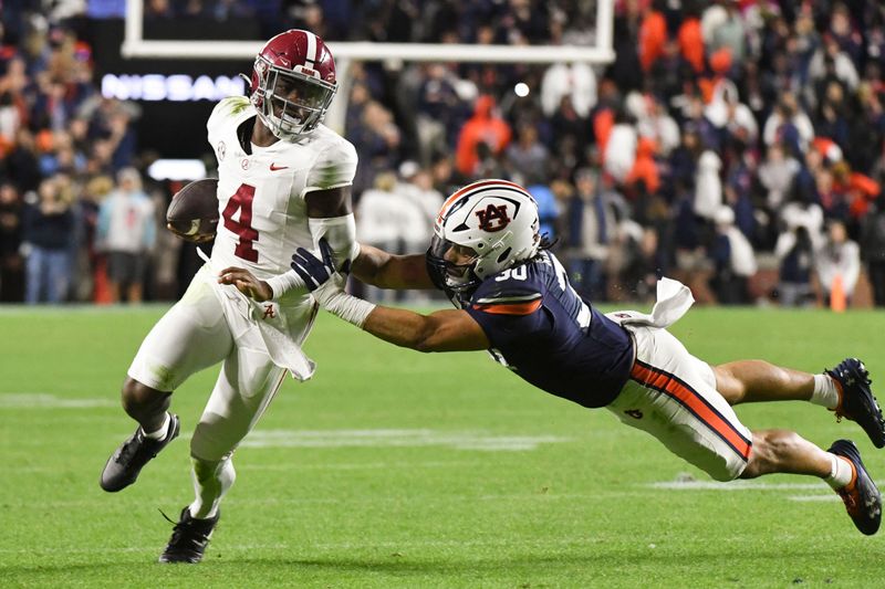 Nov 25, 2023; Auburn, Alabama, USA;  Auburn Tigers linebacker Larry Nixon III (30) shoves Alabama Crimson Tide quarterback Jalen Milroe (4) toward the sidelines at Jordan-Hare Stadium. Alabama won 27-24. Mandatory Credit: Gary Cosby Jr.-USA TODAY Sports