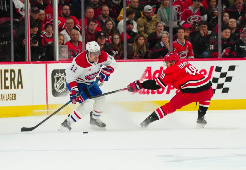 Dec 28, 2023; Raleigh, North Carolina, USA; Montreal Canadiens right wing Brendan Gallagher (11) skates with the puck against the stick check by Carolina Hurricanes center Jack Drury (18) during the first period at PNC Arena. Mandatory Credit: James Guillory-USA TODAY Sports