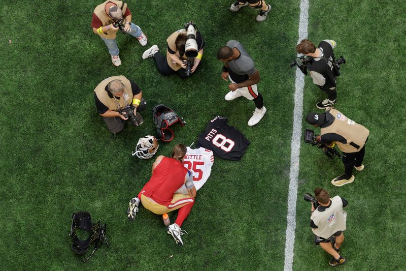 Aerial view of San Francisco 49ers tight end George Kittle (85) signing his jersey for Atlanta Falcons tight end Kyle Pitts (8) following an NFL football game, Sunday, Oct. 16, 2022, in Atlanta. (AP Photo/Stew Milne)