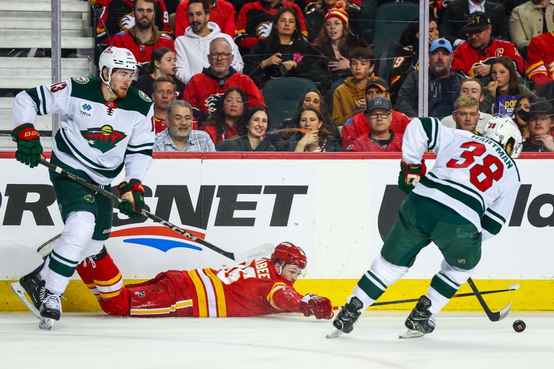 Apr 11, 2025; Calgary, Alberta, CAN; Calgary Flames left wing Joel Farabee (86) reaches for the puck against Minnesota Wild right wing Ryan Hartman (38) during the second period at Scotiabank Saddledome. Mandatory Credit: Sergei Belski-Imagn Images