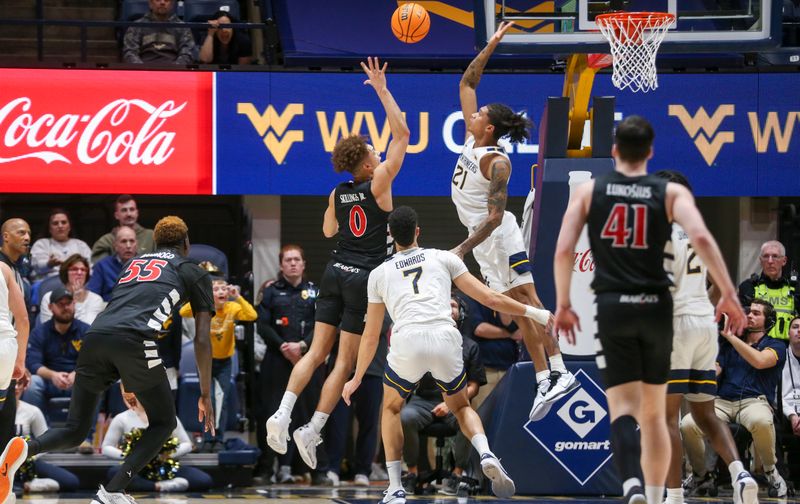 Jan 31, 2024; Morgantown, West Virginia, USA; West Virginia Mountaineers guard RaeQuan Battle (21) blocks a shot from Cincinnati Bearcats guard Dan Skillings Jr. (0) during the second half at WVU Coliseum. Mandatory Credit: Ben Queen-USA TODAY Sports