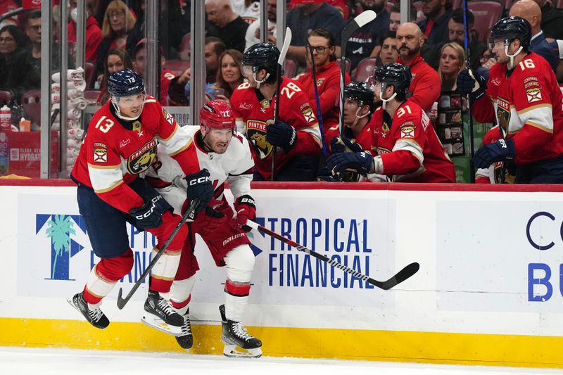 Nov 10, 2023; Sunrise, Florida, USA; Florida Panthers center Sam Reinhart (13) checks Carolina Hurricanes defenseman Brett Pesce (22) into the boards during the second period at Amerant Bank Arena. Mandatory Credit: Jasen Vinlove-USA TODAY Sports