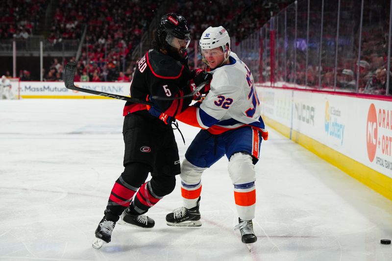 Apr 22, 2024; Raleigh, North Carolina, USA; Carolina Hurricanes defenseman Jalen Chatfield (5) checks New York Islanders center Kyle MacLean (32) during the second period in game two of the first round of the 2024 Stanley Cup Playoffs at PNC Arena. Mandatory Credit: James Guillory-USA TODAY Sports