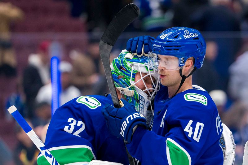 Nov 12, 2024; Vancouver, British Columbia, CAN; Vancouver Canucks goalie Kevin Lankinen (32) and forward Elias Pettersson (40) celebrate a victory against the Calgary Flames at Rogers Arena. Mandatory Credit: Bob Frid-Imagn Images