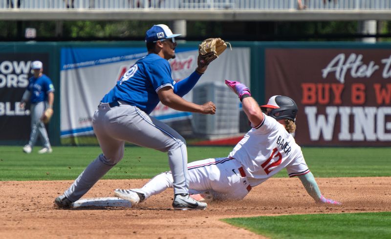 Mar 22, 2025; Fort Myers, Florida, USA; Minnesota Twins Harrison Bader(12) slides into second base just missing the tags form Toronto Blue Jays Leo Jimenez (49) at Lee Health Sports Complex. Mandatory Credit: Chris Tilley-Imagn Images