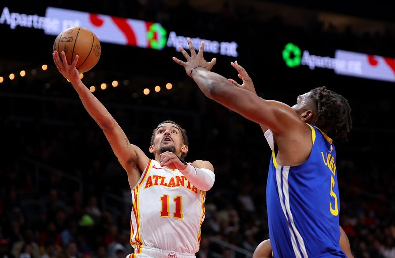 ATLANTA, GEORGIA - FEBRUARY 03:  Trae Young #11 of the Atlanta Hawks drives against Kevon Looney #5 of the Golden State Warriors during the second quarter at State Farm Arena on February 03, 2024 in Atlanta, Georgia.  NOTE TO USER: User expressly acknowledges and agrees that, by downloading and/or using this photograph, user is consenting to the terms and conditions of the Getty Images License Agreement.  (Photo by Kevin C. Cox/Getty Images)