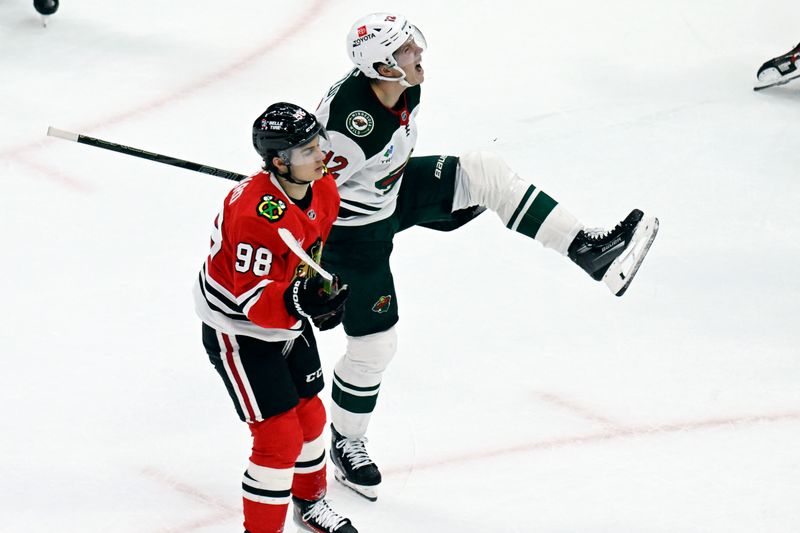 Nov 10, 2024; Chicago, Illinois, USA;  Minnesota Wild left wing Matt Boldy (12) reacts as Chicago Blackhawks center Connor Bedard (98) looks on after scoring a goal during the third  period at the United Center. Mandatory Credit: Matt Marton-Imagn Images