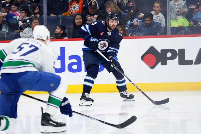 Apr 18, 2024; Winnipeg, Manitoba, CAN; Winnipeg Jets forward Alex Iafallo (9) skates in on Vancouver Canucks defenseman Tyler Myers (57) during the second period at Canada Life Centre. Mandatory Credit: Terrence Lee-USA TODAY Sports