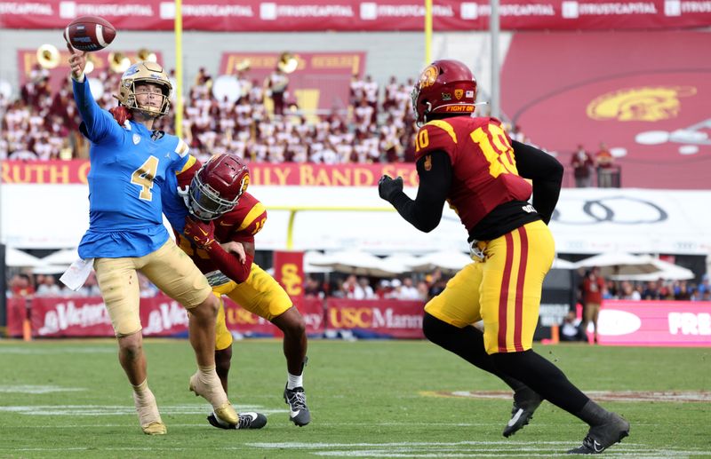 Nov 18, 2023; Los Angeles, California, USA; UCLA Bruins quarterback Ethan Garbers (4) scrambles to throw a touchdown under pressure from USC Trojans safety Jaylin Smith (19) during the third quarter at United Airlines Field at Los Angeles Memorial Coliseum. Mandatory Credit: Jason Parkhurst-USA TODAY Sports