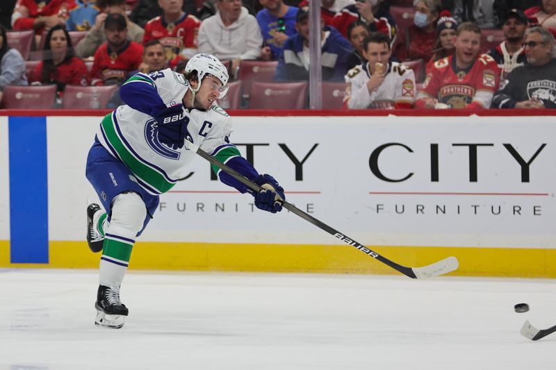 Oct 17, 2024; Sunrise, Florida, USA; Vancouver Canucks defenseman Quinn Hughes (43) shoots the puck against the Florida Panthers during the second period at Amerant Bank Arena. Mandatory Credit: Sam Navarro-Imagn Images