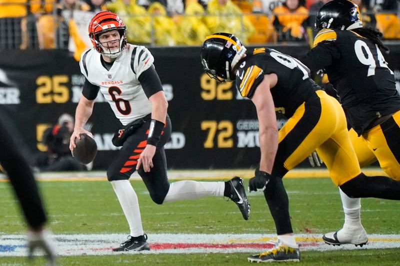 Cincinnati Bengals quarterback Jake Browning (6) rolls out looking to pass under pressure from Pittsburgh Steelers linebacker T.J. Watt (90) during an NFL football game against the Pittsburgh Steelers in Pittsburgh, Saturday Dec. 23, 2023. (AP Photo/Gene J. Puskar)