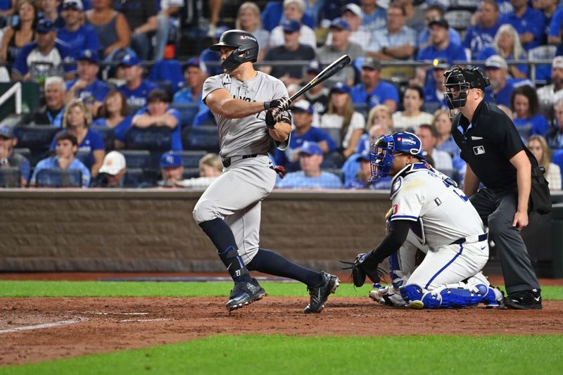 Oct 9, 2024; Kansas City, Missouri, USA; New York Yankees designated hitter Giancarlo Stanton (27) hits a single in the sixth inning against the Kansas City Royals during game three of the NLDS for the 2024 MLB Playoffs at Kauffman Stadium. Mandatory Credit: Peter Aiken-Imagn Images