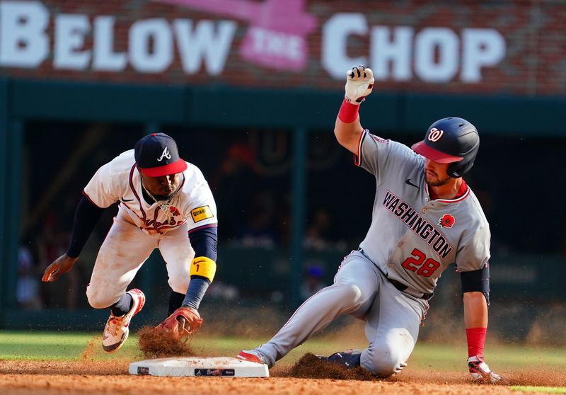 May 27, 2024; Cumberland, Georgia, USA; Washington Nationals outfielder Lane Thomas (28) slides in safely at second base against Atlanta Braves second baseman Ozzie Albies (1) during the eighth inning against the Washington Nationals at Truist Park. Mandatory Credit: John David Mercer-USA TODAY Sports