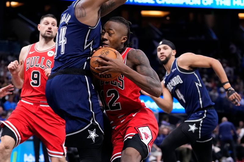 ORLANDO, FLORIDA - APRIL 07: Ayo Dosunmu #12 of the Chicago Bulls drives to the basket against Wendell Carter Jr. #34 of the Orlando Magic during the third quarter at Kia Center on April 07, 2024 in Orlando, Florida. NOTE TO USER: User expressly acknowledges and agrees that, by downloading and or using this photograph, User is consenting to the terms and conditions of the Getty Images License Agreement. (Photo by Rich Storry/Getty Images)