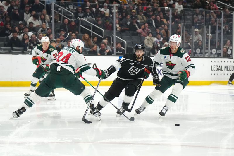 Apr 15, 2024; Los Angeles, California, USA; LA Kings center Phillip Danault (24) battles for the puck with Minnesota Wild defenseman Zach Bogosian (24) and left wing Matt Boldy (12) in the second period at Crypto.com Arena. Mandatory Credit: Kirby Lee-USA TODAY Sports