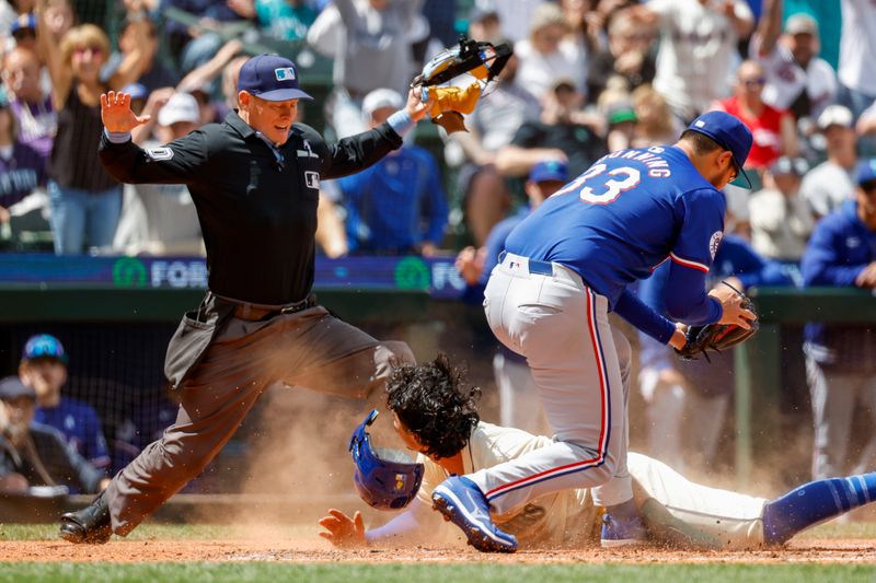 Jun 16, 2024; Seattle, Washington, USA; Home plate umpire Brian Walsh (120) calls Seattle Mariners third baseman Josh Rojas (4) safe after a slide to score a run on a wild pitch by Texas Rangers starting pitcher Dane Dunning (33) during the fifth inning at T-Mobile Park. Mandatory Credit: Joe Nicholson-USA TODAY Sports