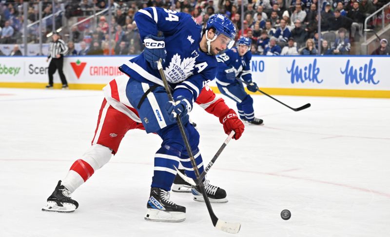 Jan 14, 2024; Toronto, Ontario, CAN;  Toronto Maple Leafs forward Auston Matthews (34) tries to get off a shot against Detroit Red Wings defenseman Jeff Petry (46) in the third period at Scotiabank Arena. Mandatory Credit: Dan Hamilton-USA TODAY Sports