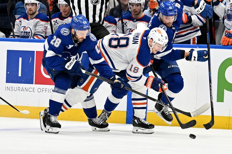 Feb 25, 2025; Tampa, Florida, USA;Tampa Bay Lightning center Zemgus Girgensons (28) and Edmonton Oilers left wing Zach Hyman (18) chase down the puck in the second period at Amalie Arena. Mandatory Credit: Jonathan Dyer-Imagn Images