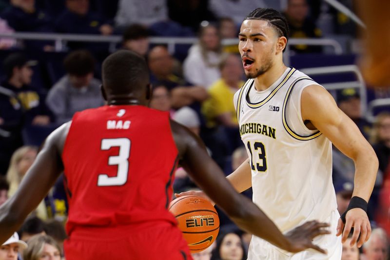 Feb 3, 2024; Ann Arbor, Michigan, USA;  Michigan Wolverines forward Olivier Nkamhoua (13) dribbles while defended by Rutgers Scarlet Knights forward Mawot Mag (3) in the first half at Crisler Center. Mandatory Credit: Rick Osentoski-USA TODAY Sports