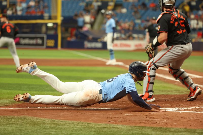 Aug 11, 2024; St. Petersburg, Florida, USA; Tampa Bay Rays designated hitter Brandon Lowe (8) slides home to score a run against the Baltimore Orioles during the eighth inning at Tropicana Field. Mandatory Credit: Kim Klement Neitzel-USA TODAY Sports