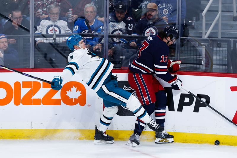 Oct 18, 2024; Winnipeg, Manitoba, CAN;  Winnipeg Jets forward Adam Lowry (17) checks San Jose Sharks forward Nico Sturm (7) during the third period at Canada Life Centre. Mandatory Credit: Terrence Lee-Imagn Images