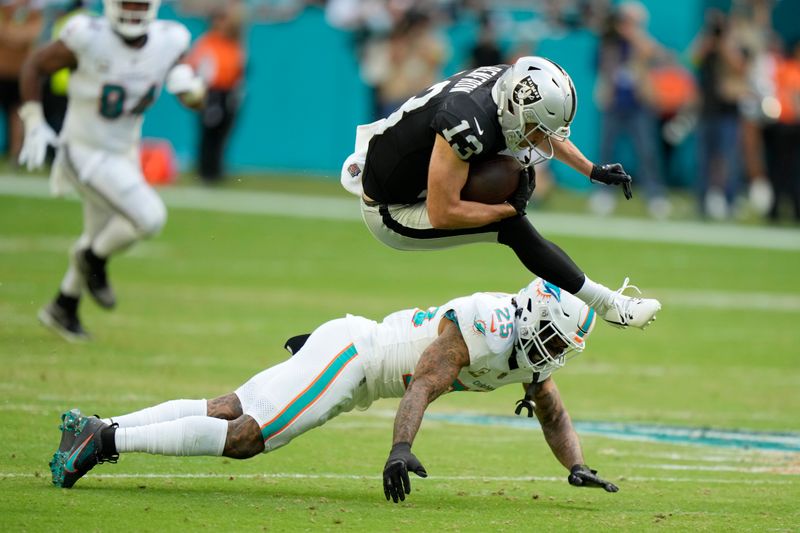 Las Vegas Raiders wide receiver Hunter Renfrow (13) leaps over Miami Dolphins cornerback Xavien Howard (25) during the second half of an NFL football game, Sunday, Nov. 19, 2023, in Miami Gardens, Fla. (AP Photo/Wilfredo Lee)