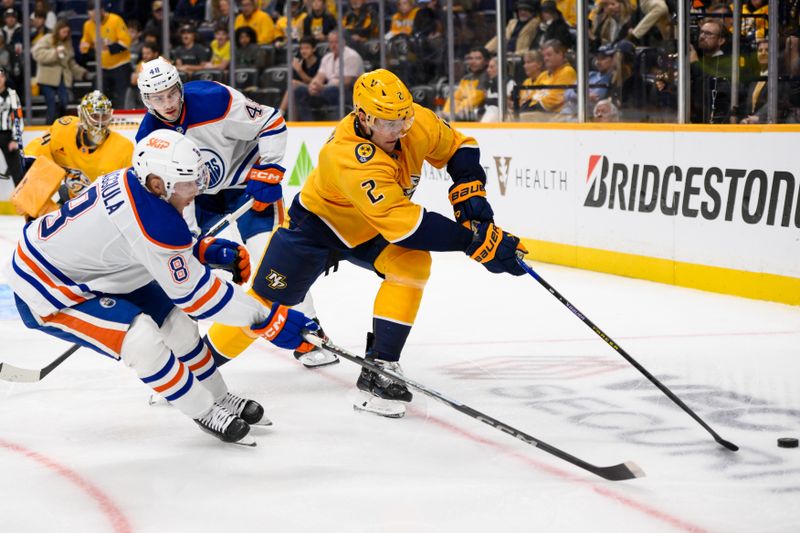 Oct 31, 2024; Nashville, Tennessee, USA;  Nashville Predators defenseman Luke Schenn (2) and Edmonton Oilers left wing Drake Caggiula (8) fight for the puck during the second period at Bridgestone Arena. Mandatory Credit: Steve Roberts-Imagn Images