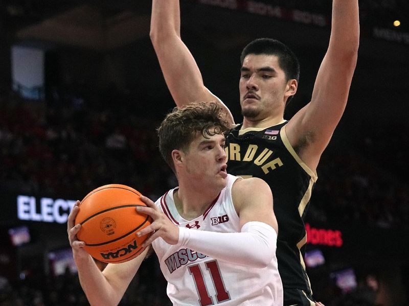 Feb 4, 2024; Madison, Wisconsin, USA; Wisconsin guard Max Klesmit (11) finds an open teammate while being guarded by Purdue center Zach Edey (15) during the second half at Kohl Center. Mandatory Credit: Mark Hoffman-USA TODAY Sports