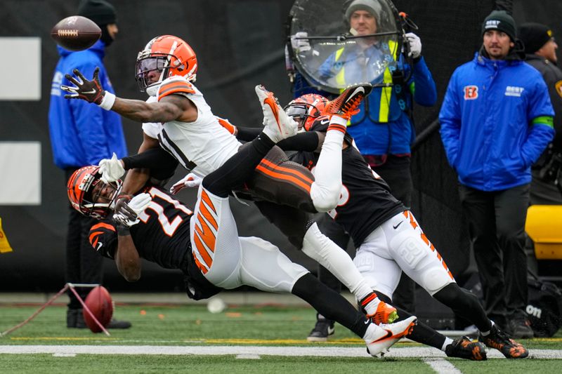 Cincinnati Bengals cornerback Mike Hilton, left, and cornerback Cam Taylor-Britt, right, break up a pass intended doe Cleveland Browns wide receiver James Proche II (11) during the first half of an NFL football game in Cincinnati, Sunday, Jan. 7, 2024. (AP Photo/Sue Ogrocki)