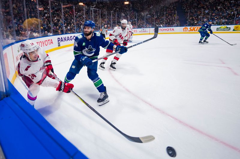 Dec 9, 2023; Vancouver, British Columbia, CAN; Vancouver Canucks forward Phillip Di Giuseppe (34) checks Carolina Hurricanes forward Seth Jarvis (24) in the first period at Rogers Arena. Mandatory Credit: Bob Frid-USA TODAY Sports