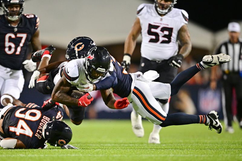 Houston Texans running back Cam Akers, center left, is tackled by Chicago Bears cornerback Josh Blackwell, center right, during the first half of an NFL exhibition Hall of Fame football game Thursday, Aug. 1, 2024, in Canton, Ohio. (AP Photo/David Dermer)