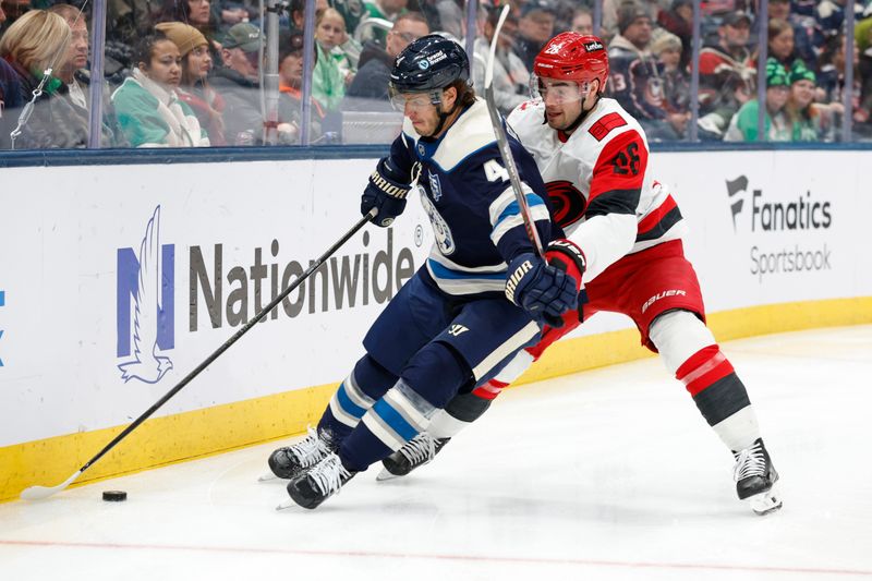 Mar 17, 2026; Columbus, Ohio, USA; Columbus Blue Jackets center Cole Sillinger (4) takes control of the puck as Carolina Hurricanes defenseman Sean Walker (26) defends during the second period at Nationwide Arena. Mandatory Credit: Russell LaBounty-Imagn Images