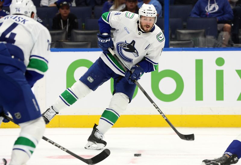 Oct 15, 2024; Tampa, Florida, USA; Vancouver Canucks center J.T. Miller (9) passes the puck against the Tampa Bay Lightning during the second period at Amalie Arena. Mandatory Credit: Kim Klement Neitzel-Imagn Images