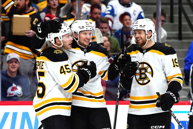 Oct 16, 2024; Denver, Colorado, USA; Boston Bruins left wing Cole Koepke (45) celebrates his goal with defenseman Andrew Peeke (52) and center John Beecher (19) in the first period against the Colorado Avalanche at Ball Arena. Mandatory Credit: Ron Chenoy-Imagn Images