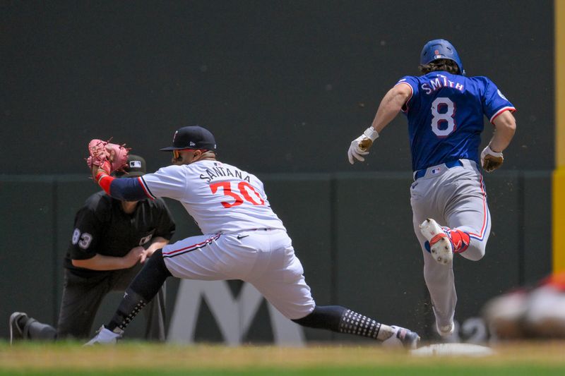 May 25, 2024; Minneapolis, Minnesota, USA;  Minnesota Twins infielder Carlos Santana (30) catches the ball to force out Texas Rangers infielder Josh H. Smith (8) at first base during the fourth inning at Target Field. Mandatory Credit: Nick Wosika-USA TODAY Sports