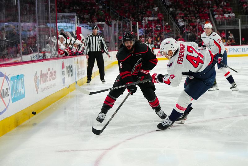 Apr 5, 2024; Raleigh, North Carolina, USA; Washington Capitals defenseman Martin Fehervary (42) chips the puck away from Carolina Hurricanes defenseman Jalen Chatfield (5) during the third period at PNC Arena. Mandatory Credit: James Guillory-USA TODAY Sports